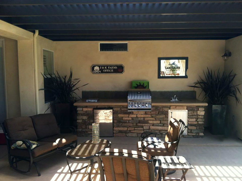 Outdoor kitchen with sink and sitting area under covered patio