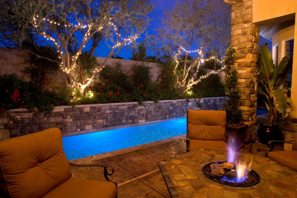 custom stone retaining wall and pool with olive trees in planter